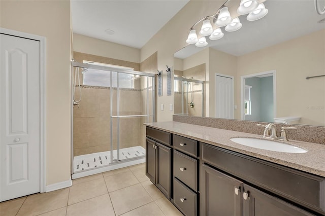 bathroom with a shower with door, vanity, and tile patterned floors