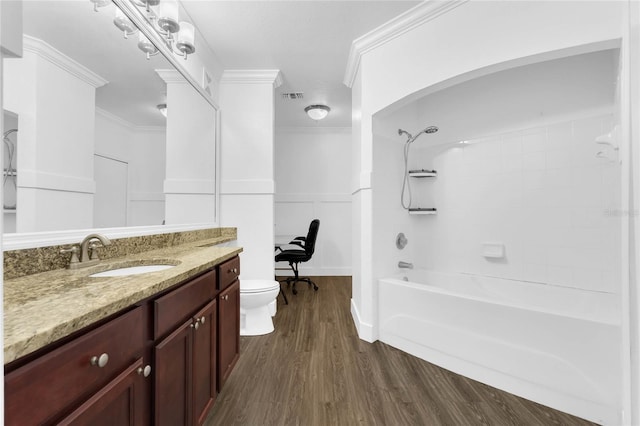 full bathroom with hardwood / wood-style floors, vanity, tiled shower / bath, crown molding, and toilet