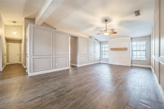 unfurnished living room with dark hardwood / wood-style floors, lofted ceiling with beams, a textured ceiling, and ceiling fan