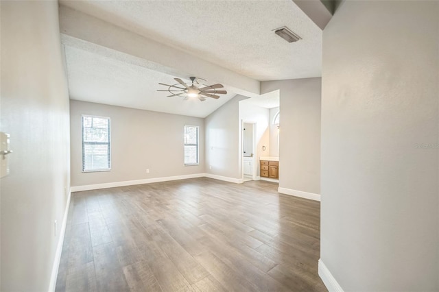 interior space with ceiling fan, vaulted ceiling with beams, wood-type flooring, and a textured ceiling