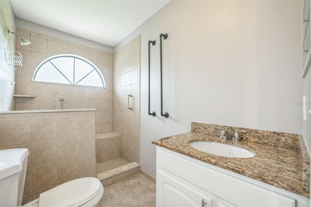 bathroom with tile patterned floors, vanity, tiled shower, and toilet