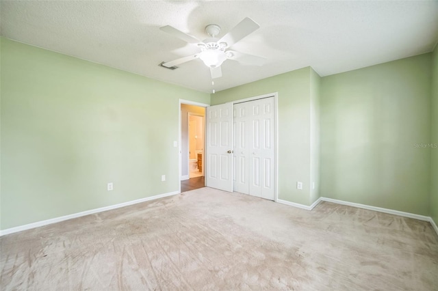 unfurnished bedroom featuring ceiling fan, a textured ceiling, a closet, and light carpet