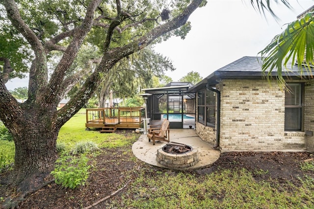 view of yard featuring an outdoor fire pit, a patio, glass enclosure, and a swimming pool side deck