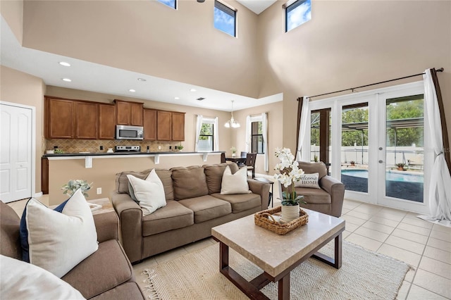 tiled living room with a high ceiling, french doors, and a chandelier