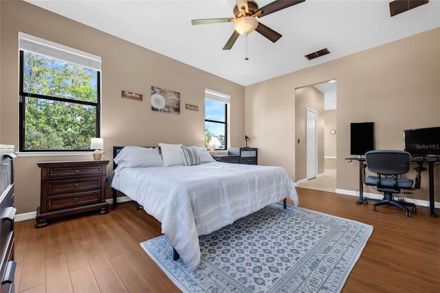 bedroom with multiple windows, ceiling fan, and wood-type flooring