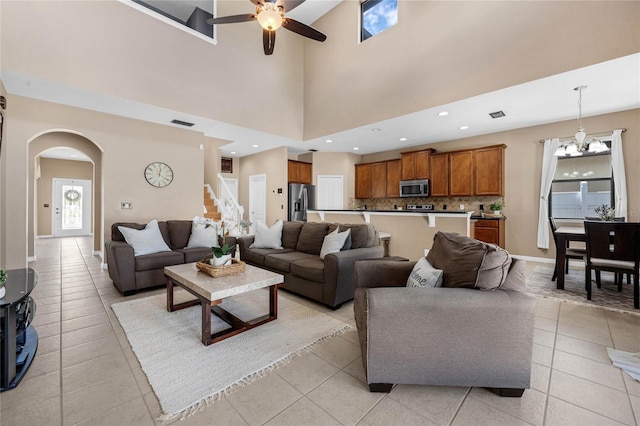 living room featuring light tile patterned floors, baseboards, arched walkways, visible vents, and stairway