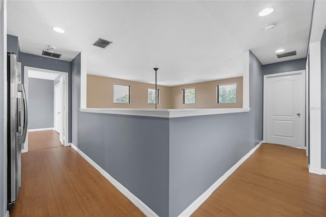 corridor with baseboards, visible vents, wood finished floors, and recessed lighting