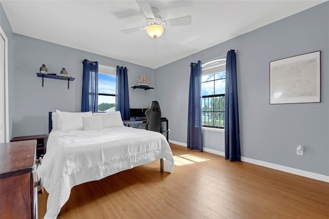 bedroom with multiple windows, ceiling fan, and hardwood / wood-style floors