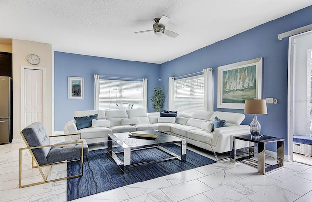 living room with ceiling fan and a textured ceiling