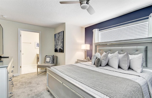 bedroom featuring light carpet, ceiling fan, ensuite bathroom, and a textured ceiling