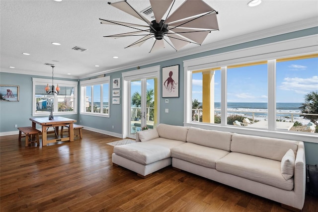 living room featuring a water view, a textured ceiling, dark wood-type flooring, and ornamental molding