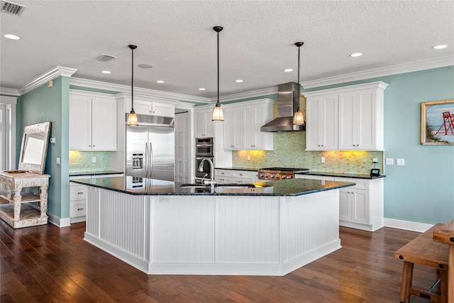 kitchen with wall chimney range hood, a large island, stainless steel appliances, decorative light fixtures, and dark wood-type flooring