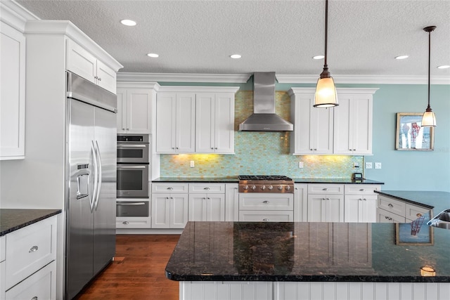 kitchen with crown molding, stainless steel appliances, wall chimney exhaust hood, and hanging light fixtures