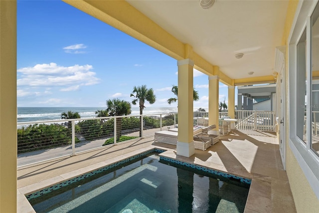 exterior space with a hot tub, a balcony, a water view, and a beach view