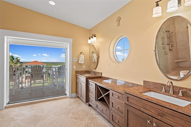 bathroom with a tile shower, lofted ceiling, plenty of natural light, and vanity