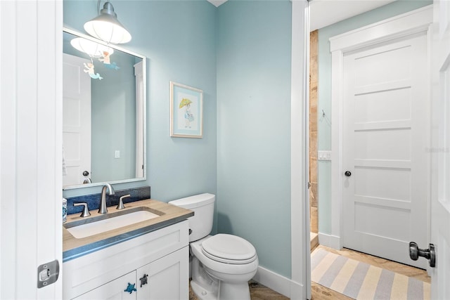 bathroom featuring toilet, vanity, and a shower