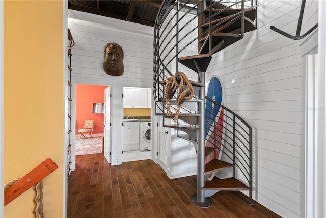 staircase with washer / dryer, hardwood / wood-style flooring, and wood walls