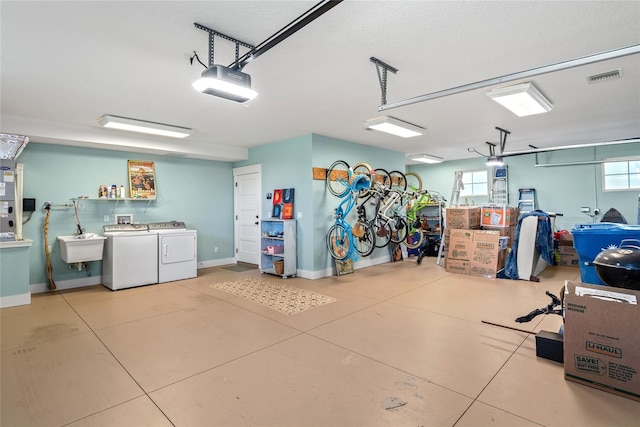 garage with sink, a garage door opener, and washing machine and clothes dryer