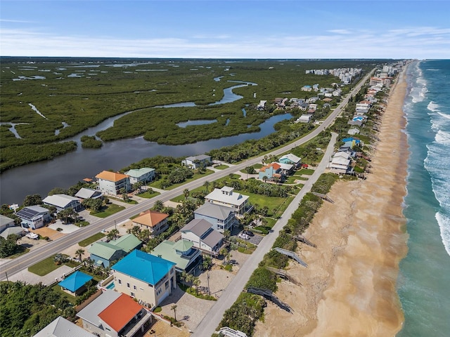 birds eye view of property featuring a water view and a beach view