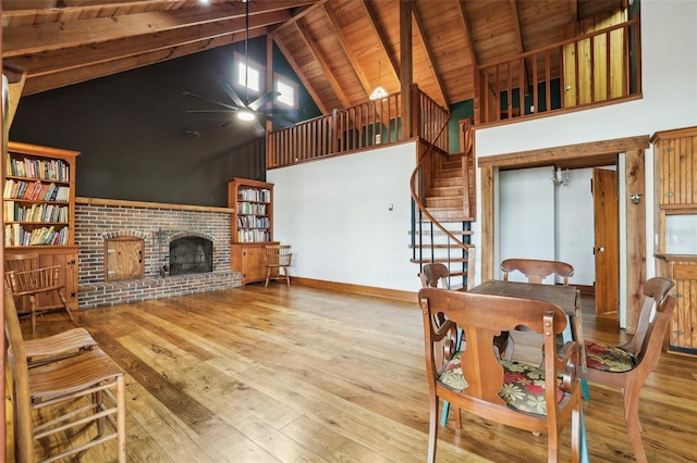 living room featuring beam ceiling, high vaulted ceiling, wooden ceiling, a fireplace, and hardwood / wood-style floors