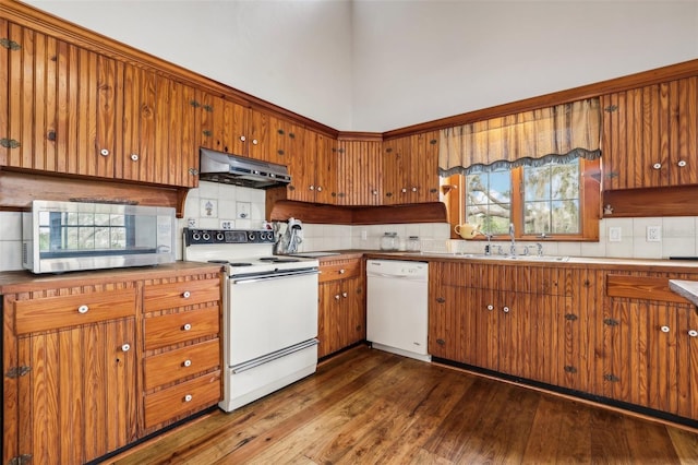 kitchen featuring white appliances, backsplash, dark wood-type flooring, sink, and range hood