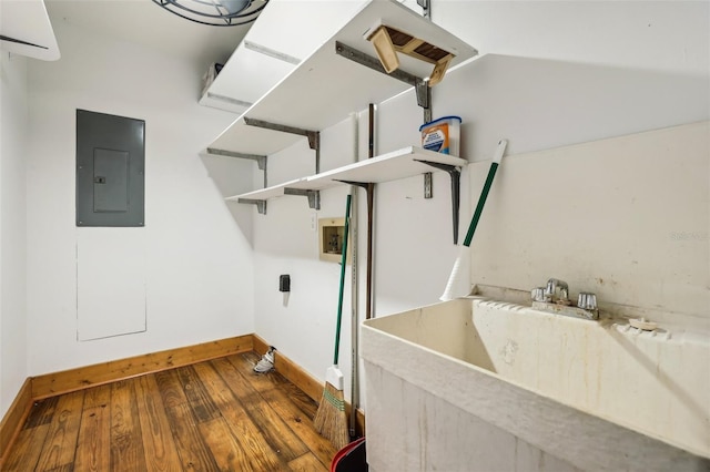 clothes washing area featuring wood-type flooring, sink, and electric panel