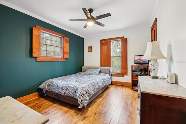 bedroom featuring ornamental molding, baseboards, light wood finished floors, and ceiling fan