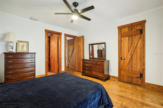 bedroom featuring baseboards, light wood-type flooring, crown molding, and visible vents