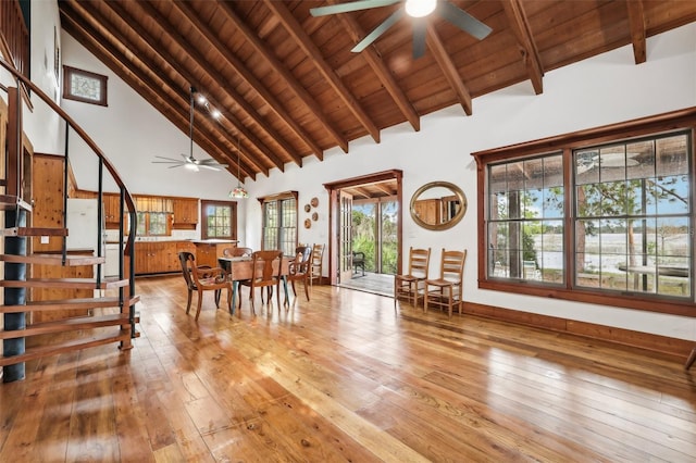 dining room featuring light wood-style flooring, stairs, beam ceiling, ceiling fan, and wooden ceiling