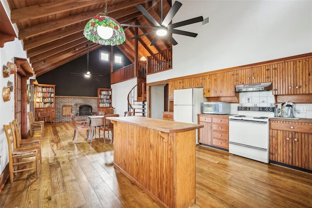 kitchen with a brick fireplace, ceiling fan, white appliances, under cabinet range hood, and light wood-style flooring