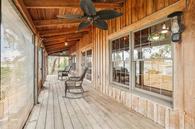unfurnished sunroom with a ceiling fan and beam ceiling