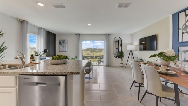 kitchen featuring dishwasher, light stone countertops, plenty of natural light, and white cabinetry