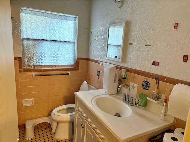 bathroom with vanity, tile patterned flooring, toilet, and tile walls