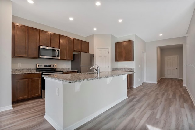 kitchen featuring light hardwood / wood-style floors, stainless steel appliances, a kitchen breakfast bar, and an island with sink