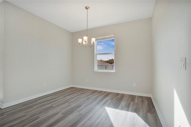 empty room with a notable chandelier and wood-type flooring