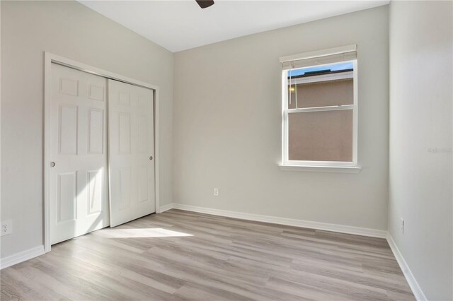 unfurnished bedroom with a closet, light hardwood / wood-style flooring, multiple windows, and ceiling fan