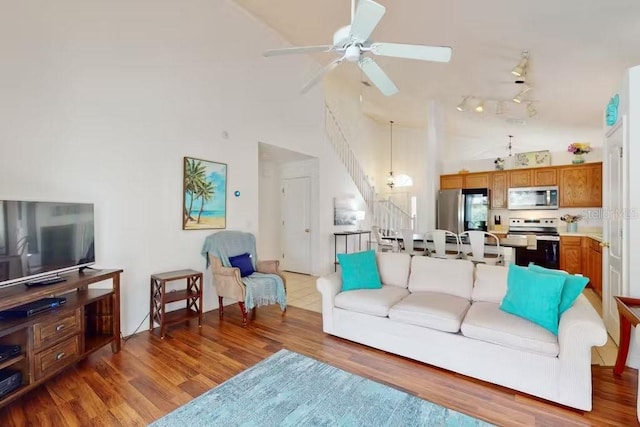 living room with dark wood-type flooring, a high ceiling, and ceiling fan with notable chandelier