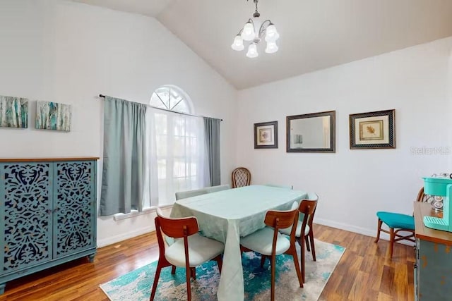 dining space with an inviting chandelier, lofted ceiling, and hardwood / wood-style floors