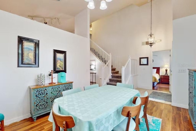 dining area featuring a towering ceiling, a notable chandelier, and light hardwood / wood-style floors