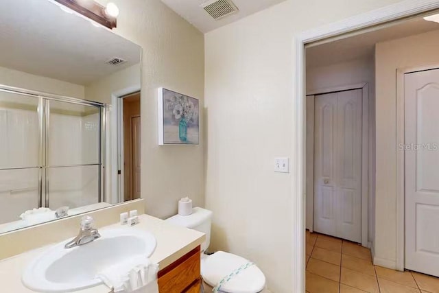 bathroom with vanity, an enclosed shower, toilet, and tile patterned floors