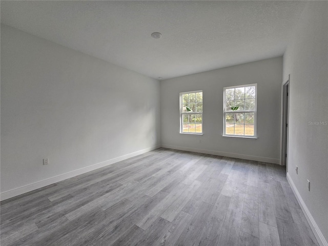 spare room featuring a textured ceiling and light hardwood / wood-style floors