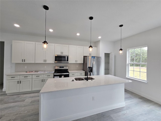 kitchen featuring appliances with stainless steel finishes, white cabinetry, sink, and an island with sink