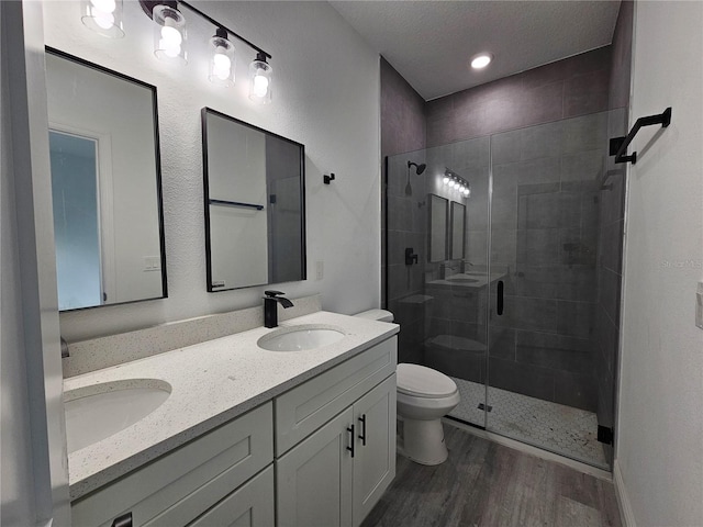 bathroom with toilet, wood-type flooring, vanity, a textured ceiling, and an enclosed shower