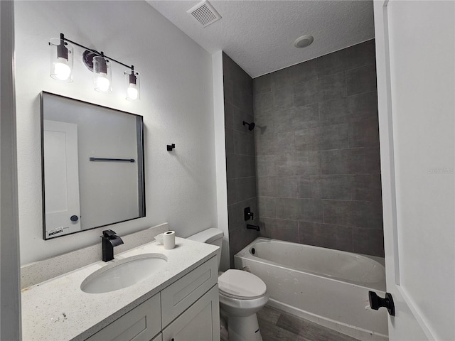 full bathroom with vanity, toilet, tiled shower / bath combo, and a textured ceiling