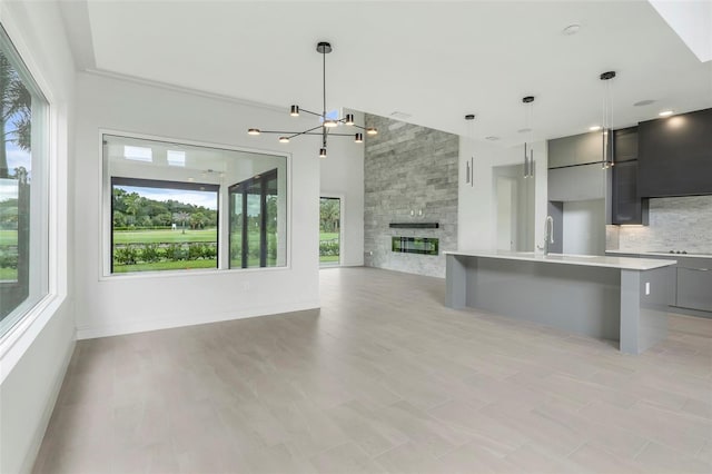 kitchen with a kitchen bar, hanging light fixtures, a fireplace, and light wood-type flooring