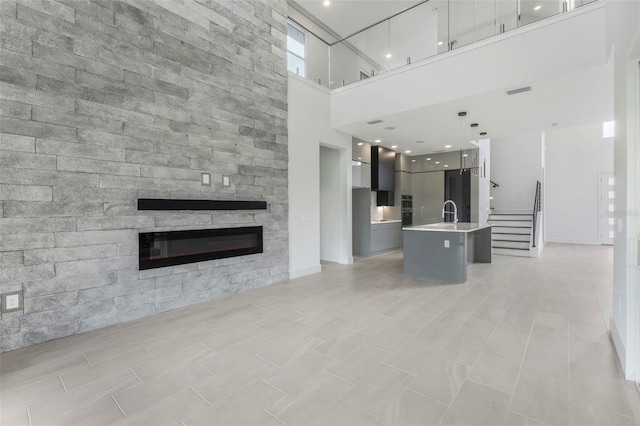 unfurnished living room with sink and a towering ceiling