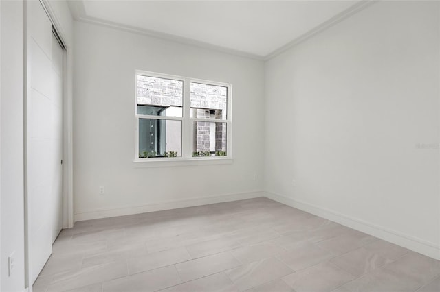 tiled spare room featuring ornamental molding