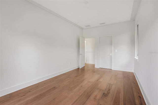 empty room featuring crown molding and light hardwood / wood-style flooring