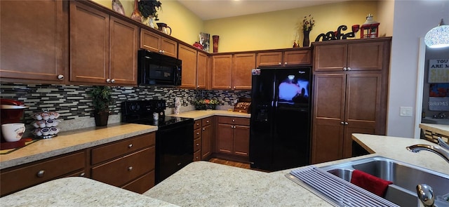 kitchen with light stone counters, black appliances, sink, and decorative backsplash