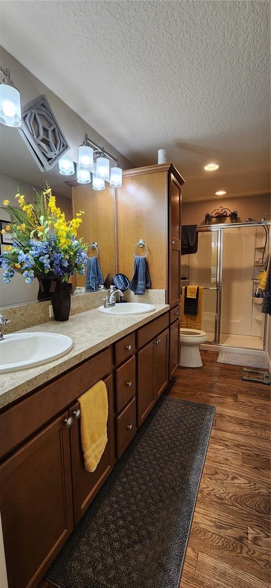 bathroom with vanity, hardwood / wood-style flooring, walk in shower, and a textured ceiling